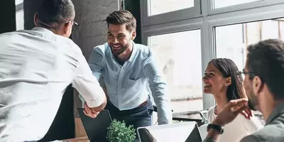 To menn tar hverandre i hånden under et møte. Foto