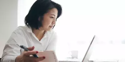 En dame sitter og ser på en laptop. Foto