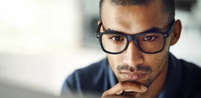 En mann holder hånden til haken. Foto