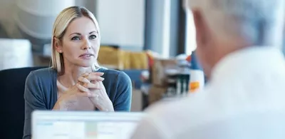 En dame sitter overfor en mann og prater. Foto