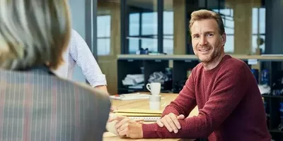 En mann sitter rundt et møtebord. Foto