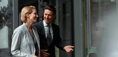 En mann og en dame går utendørs og prater. Foto