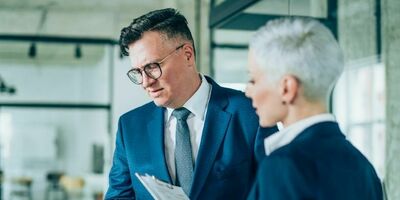 En mann og en dame i dress står ved siden av hverandre. Foto