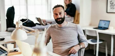 En mann sitter i et kontorlandskap. Foto