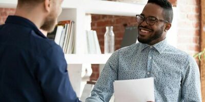 To menn tar hverandre i hånden og smiler. Foto